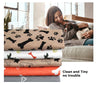 Stack of colorful 3-layer waterproof pet pads with bone and paw prints design beside woman cuddling dog on couch
