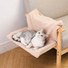 Plush L-shaped cat hammock in beige hanging on wooden armchair with gray and white cat lounging