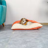 Small dog resting in removable and washable bite resistant pet sleeping bag with soft orange and cream fabric