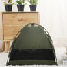 Portable green cat tent with breathable mesh and black cooling mat for indoor use next to wooden cabinet and white curtain background
